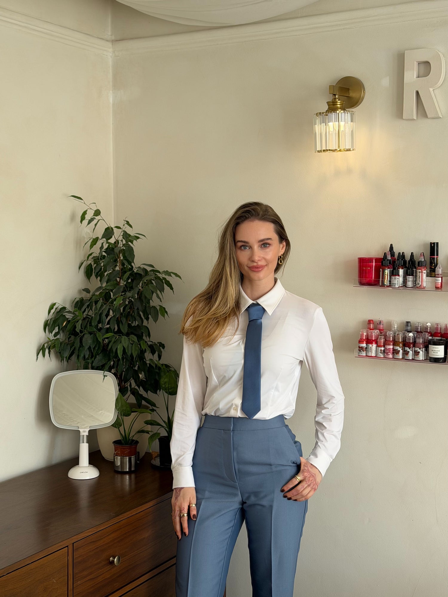 Woman in a white shirt and blue tie standing in an office setting.